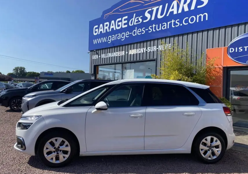 Vue de profil côté gauche d'une Citroën C4 Spacetourer blanche stationnée devant un garage.