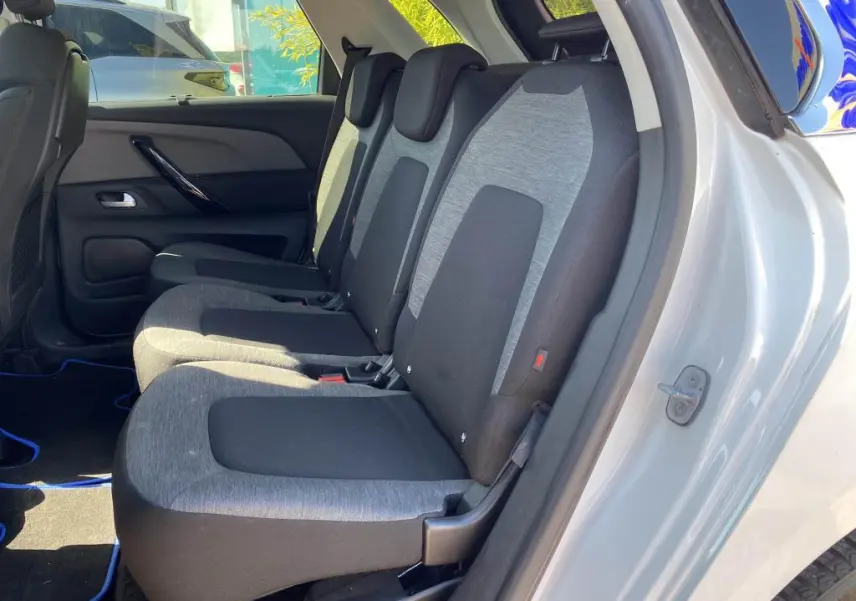 Vue latérale intérieure sur les sièges arrière gris et noirs du Citroën C4 Spacetourer blanc, porte arrière ouverte.