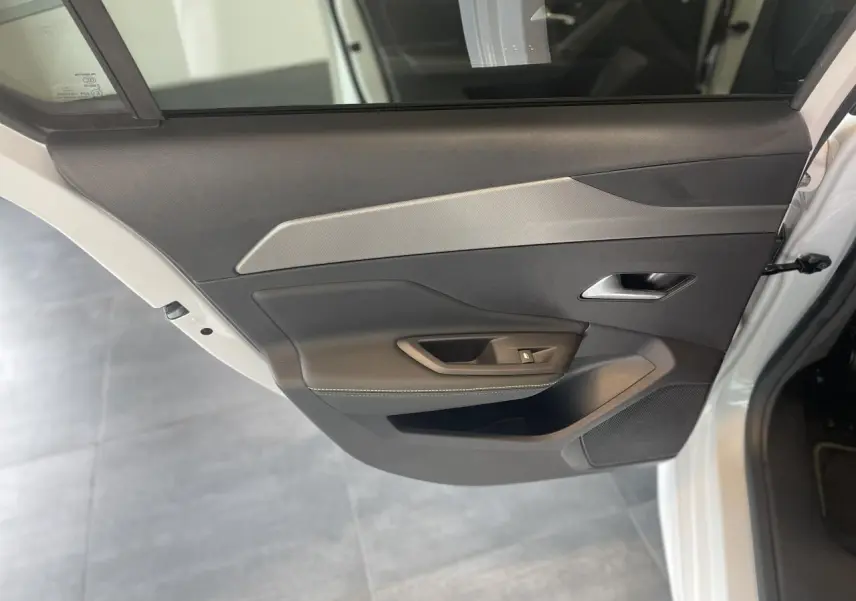 Vue côté gauche de la porte arrière blanche d'une Peugeot 308 GT 2025 avec insert décor aluminium et poignée intégrée.