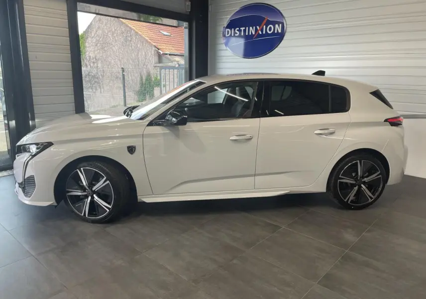 Profil côté gauche d'une Peugeot 308 blanche 2025 en finition GT avec jantes alliage noires et toit noir brillant.