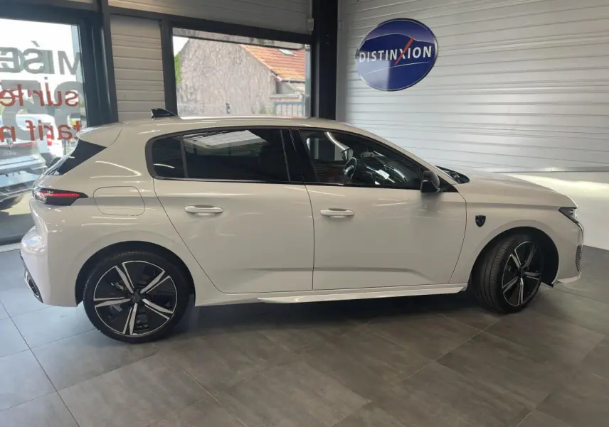 Profil côté gauche d'une Peugeot 308 blanche 2025 en berline GT, avec jantes alliage noires et toit noir brillant.