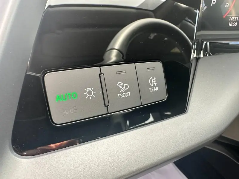 Boutons de commande d'éclairage avec mode auto vert, sur tableau de bord noir et gris d'une Audi A3 Sportback blanche 2024.