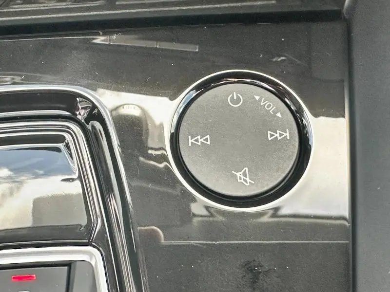 Gros plan sur la molette de contrôle du volume noire brillante dans l'habitacle de l'Audi A3 Sportback blanc Arkona 2024.