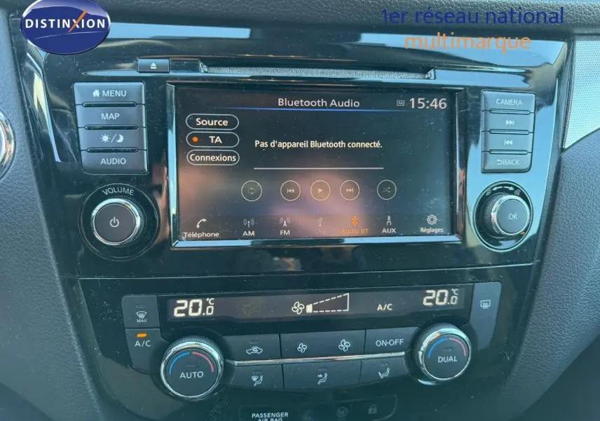 Tableau de bord de Nissan Qashqai blanc nacré, affichage central tactile avec options Bluetooth et climatisation réglée à 20°C.