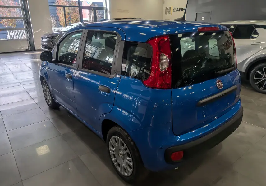 Vue 3/4 arrière droite d'une FIAT Panda 1.0 70 CH Hybrid City bleu Italia en showroom, avec feux arrière rouges et vitres teintées.