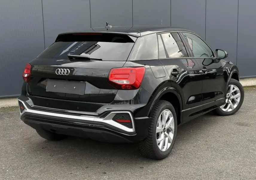 Audi Q2 noir Mythe vue 3/4 arrière droit, hayon électrique et feux arrière LED distinctifs visibles.
