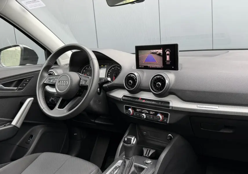 Intérieur de l'Audi Q2 35 TFSI S-Line 2023 vu côté conducteur, avec tableau de bord et écran caméra de recul allumé.