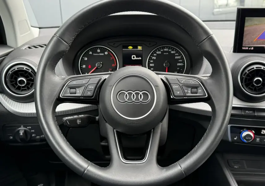 Vue centrée sur le volant noir de l'Audi Q2 35 TFSI S-Line 2023 avec tableau de bord et commandes intégrées visibles.