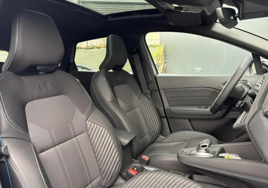 Vue intérieure côté conducteur du Renault Captur Esprit Alpine 2025, sièges noirs avec logo Alpine et toit ouvrant électrique.
