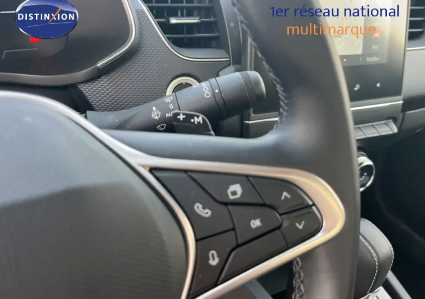 Gros plan sur le volant et commandes multifonctions du Renault Arkana gris Cassiopée, intérieur moderne avec tableau de bord visible.