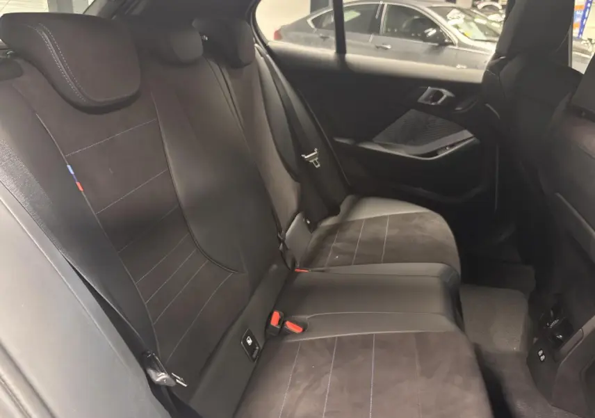 Vue intérieure côté droit des sièges arrière en Alcantara noir avec surpiqûres bleues d'une BMW Série 1 118d M Sport 2025.