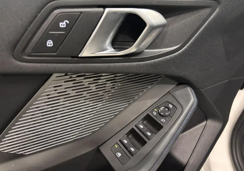 Détail de la porte avant gauche noire de la BMW Série 1 118d M Sport 2025 avec commandes de vitres et haut-parleur intégré.