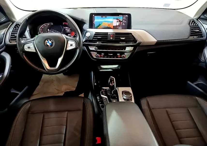 Vue intérieure avant du BMW X3 2019 noir, tableau de bord avec écran tactile et volant cuir multifonctions.