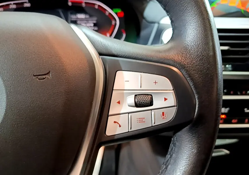 Gros plan sur les commandes multifonctions côté droit du volant cuir noir du BMW X3 sDrive18d 2019, tableau de bord en arrière-plan.