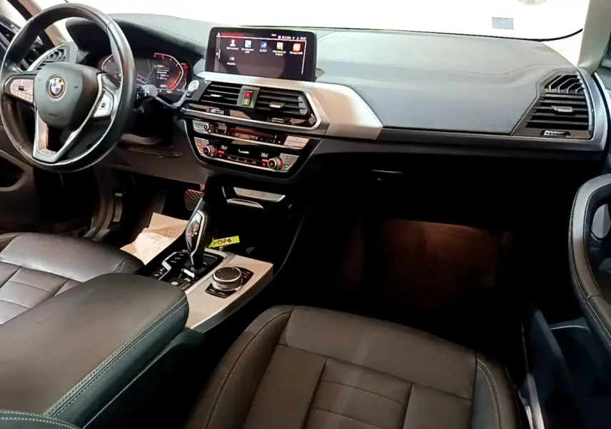 Intérieur noir de BMW X3 2019 vu de face, avec tableau de bord digital et console centrale tactile.