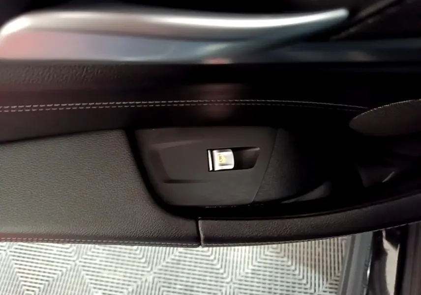 Détail de la commande de condamnation centralisée sur la porte intérieure côté conducteur d’un BMW X3 noir.