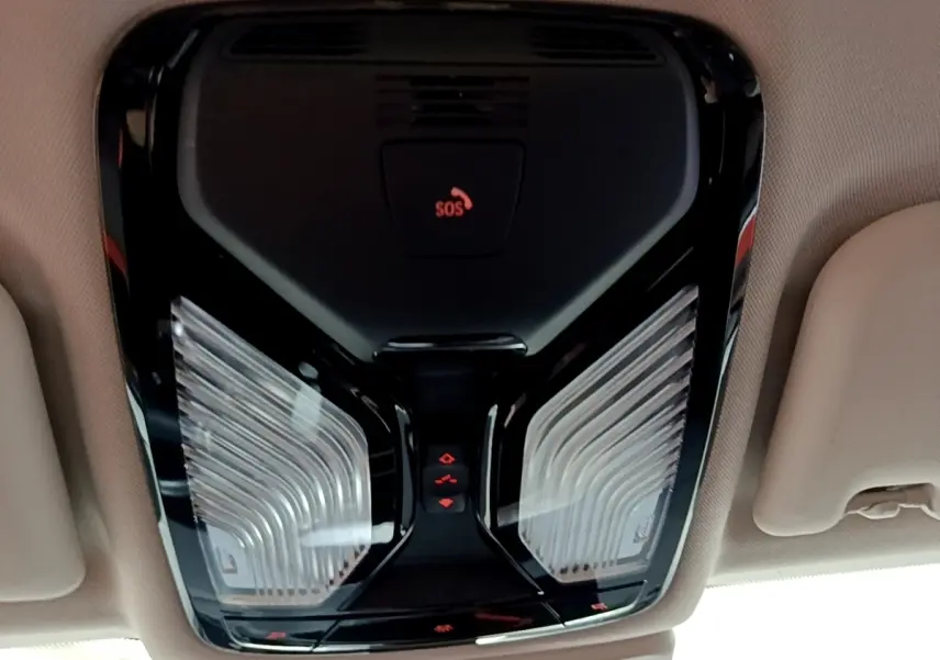 Plafonnier intérieur noir avec boutons de commande et témoin SOS, vue en contre-plongée dans un BMW X3 noir.