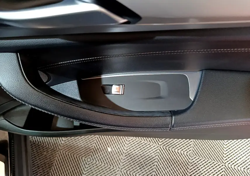 Détail de la poignée intérieure noire côté porte avant d’une BMW X3 sDrive18d 2019 avec bouton de verrouillage.