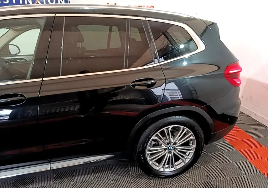 Vue latérale droite sur l’arrière d’un BMW X3 noir 2019 avec jante alliage et feux arrière LED allumés.