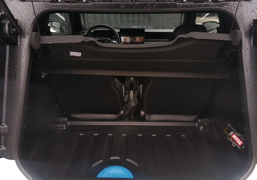 Vue depuis le coffre ouvert du Ligier JS50 blanc glacier 2026, montrant l’intérieur noir et la console centrale.