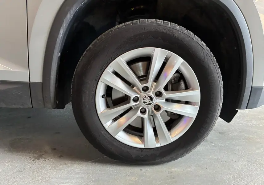 Gros plan sur la roue avant gauche d'un Skoda Kodiaq gris clair, mettant en valeur la jante alliage et le pneu hiver.
