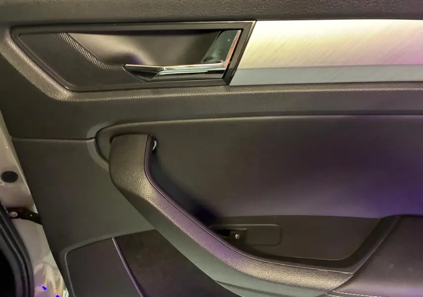 Détail de la porte intérieure côté gauche du Skoda Kodiaq gris clair, avec poignée noire et insert aluminium brossé.