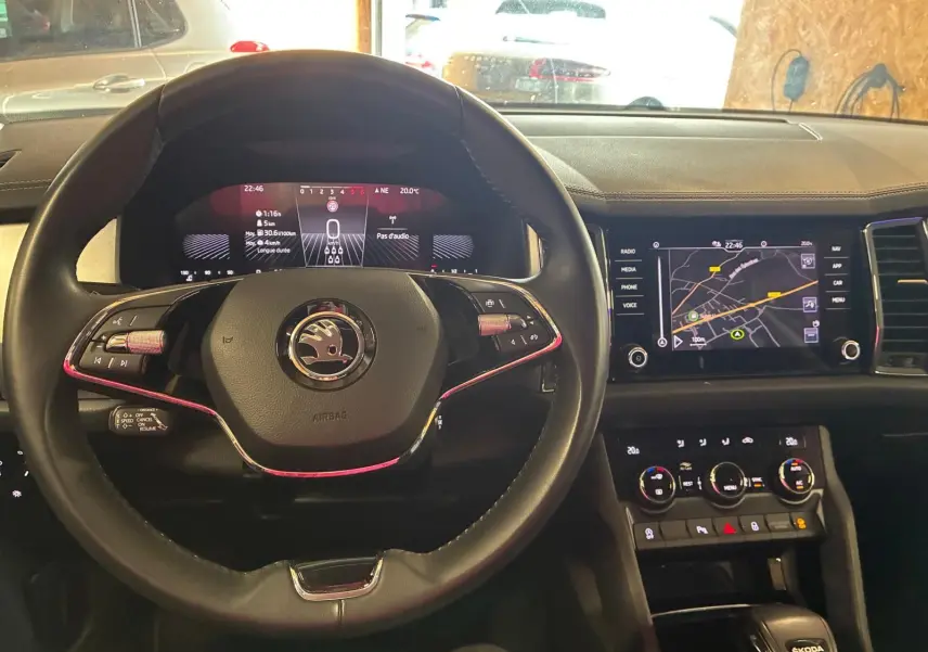 Vue intérieure centrée sur le volant noir et le tableau de bord numérique du Skoda Kodiaq gris clair 2023 avec écran GPS tactile.