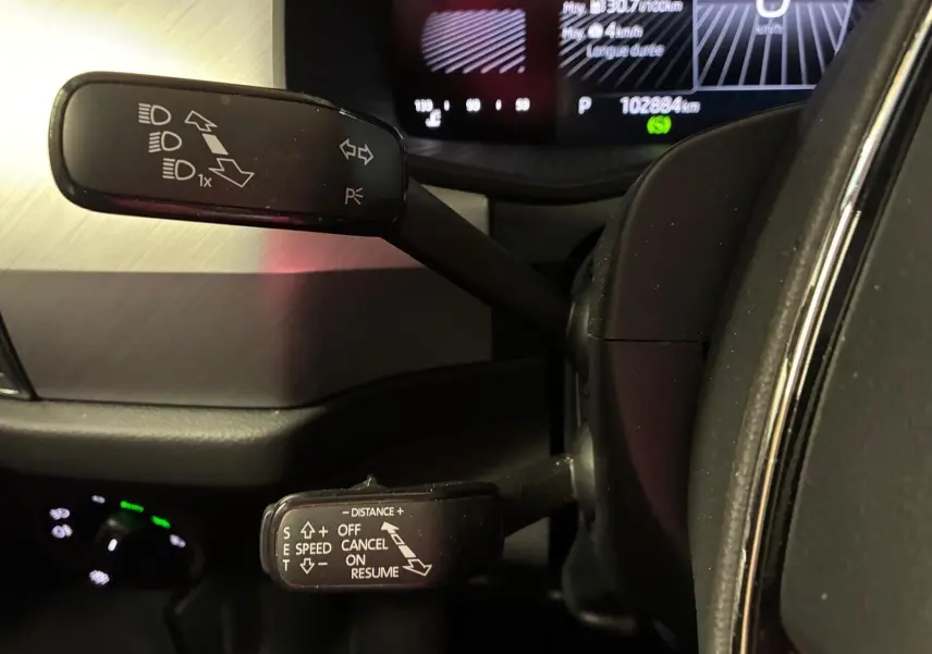 Gros plan sur les commandes au volant du Skoda Kodiaq gris clair 2023, avec affichage digital en arrière-plan.