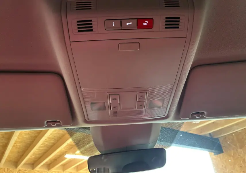 Vue intérieure du plafond avant d'un Skoda Kodiaq gris clair 2023, montrant les commandes d'éclairage et le bouton SOS.