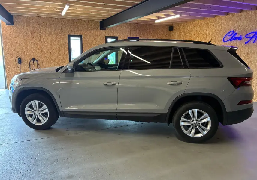 Profil droit d'un Skoda Kodiaq gris clair 2023, SUV 7 places avec jantes alliage et vitres teintées, en intérieur.