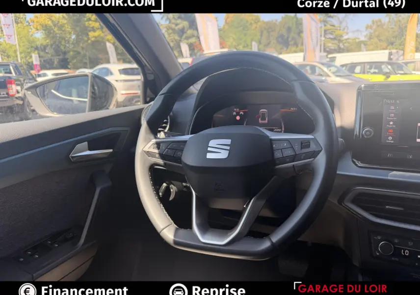 Vue intérieure centrée sur le volant cuir noir et le tableau de bord digital d'une SEAT Arona 2025.