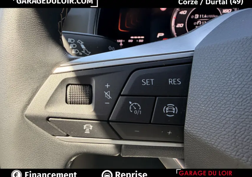 Gros plan sur les commandes multifonctions noires du volant du SEAT Arona 2025, avec affichage digital en arrière-plan.