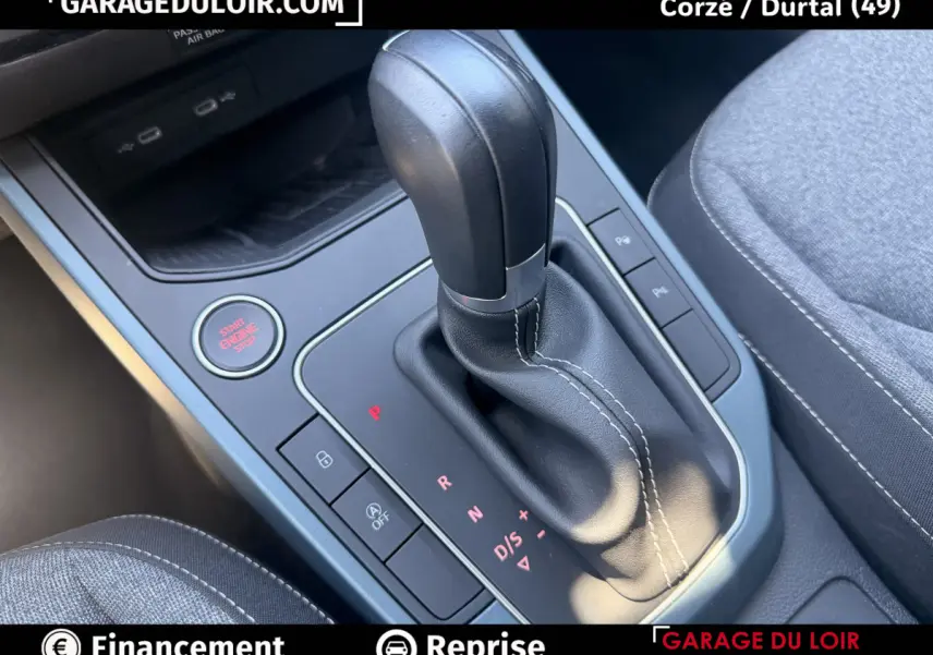 Gros plan sur la commande de boîte automatique noire avec coutures blanches et bouton start/stop rouge dans l'habitacle du SEAT Arona.