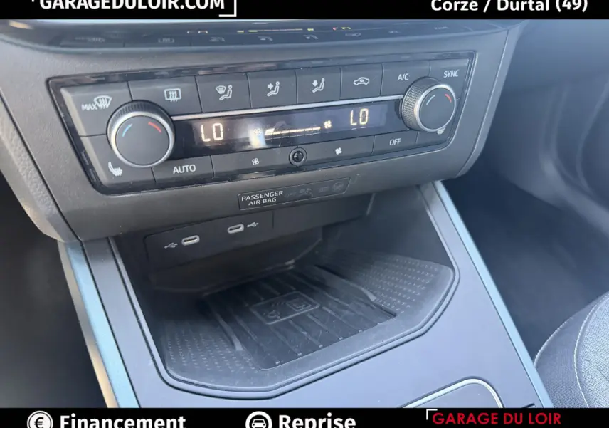 Gros plan sur la console centrale du SEAT Arona 2025 noire, avec commandes climatisation et ports USB visibles.