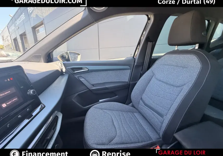 Vue intérieure côté passager avant du SEAT Arona 2025, siège gris tissu et tableau de bord avec écran tactile.