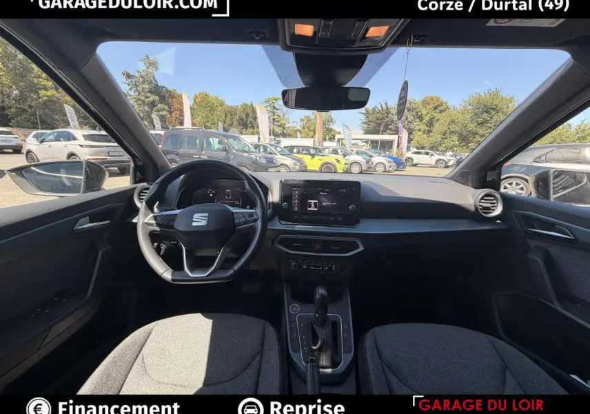 Vue intérieure avant du SEAT Arona noir 2025, tableau de bord moderne avec écran tactile et volant multifonctions.
