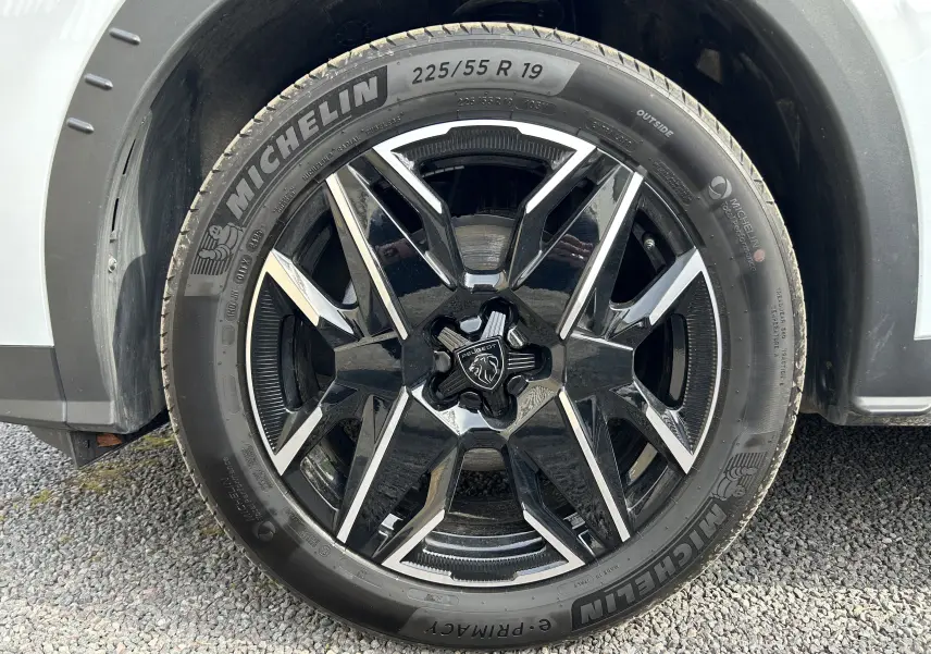 Gros plan sur la roue avant gauche du Peugeot 3008 blanc Okenite, jante alliage noire et argent avec pneu Michelin.