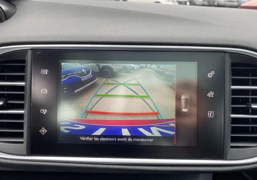 Écran central montrant la caméra de recul active d'une Peugeot 308 rouge avec lignes de guidage colorées.