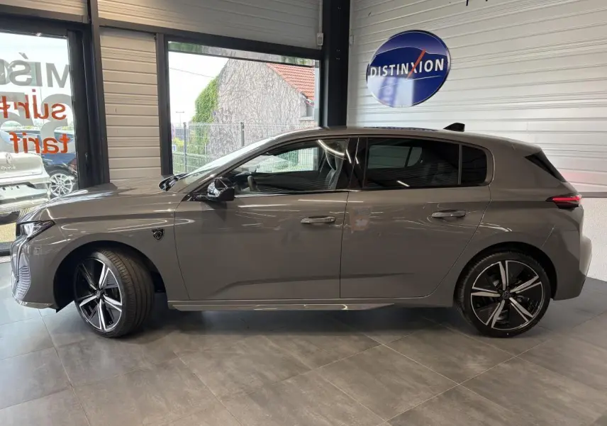 Profil côté gauche de la Peugeot 308 gris sélénium avec jantes alliage 18'' et vitres surteintées en showroom.