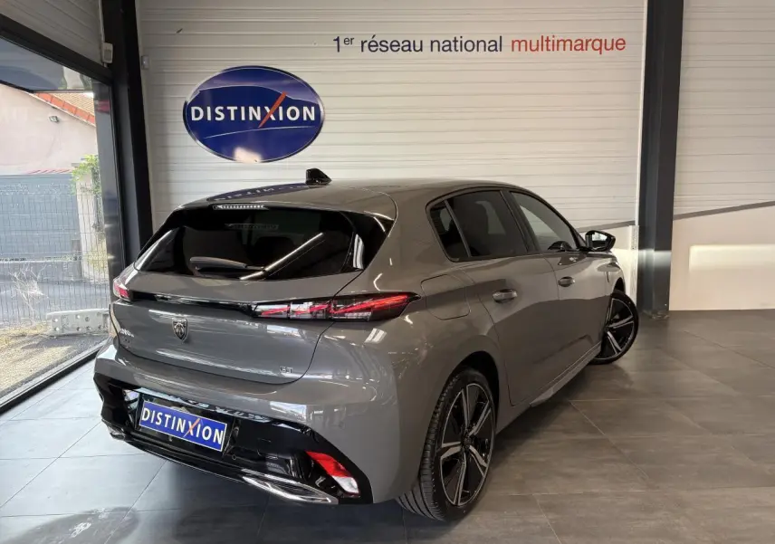 Vue 3/4 arrière droit d'une Peugeot 308 GT gris sélénium avec jantes alliage 18'' et bandeau noir brillant entre feux arrière.