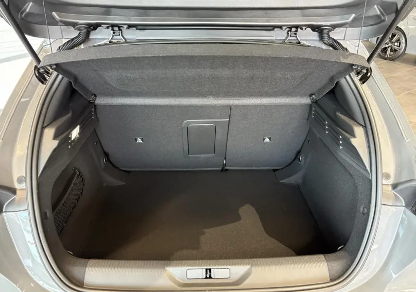 Coffre ouvert vu de l'arrière d'une Peugeot 308 gris selenium, montrant l'espace de chargement vide et propre.