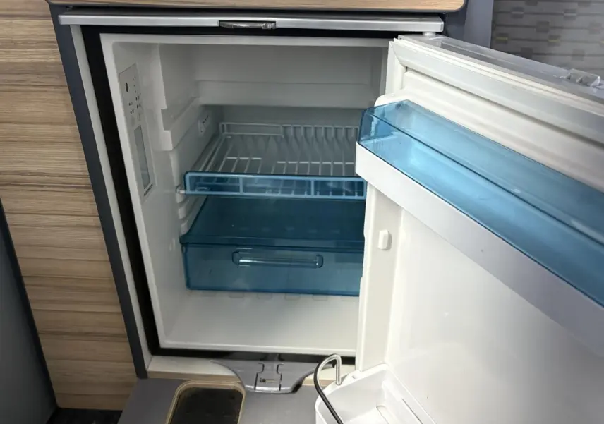 Gros plan sur le frigo ouvert intégré dans l'aménagement intérieur du Volkswagen Transporter jaune et blanc 2017.