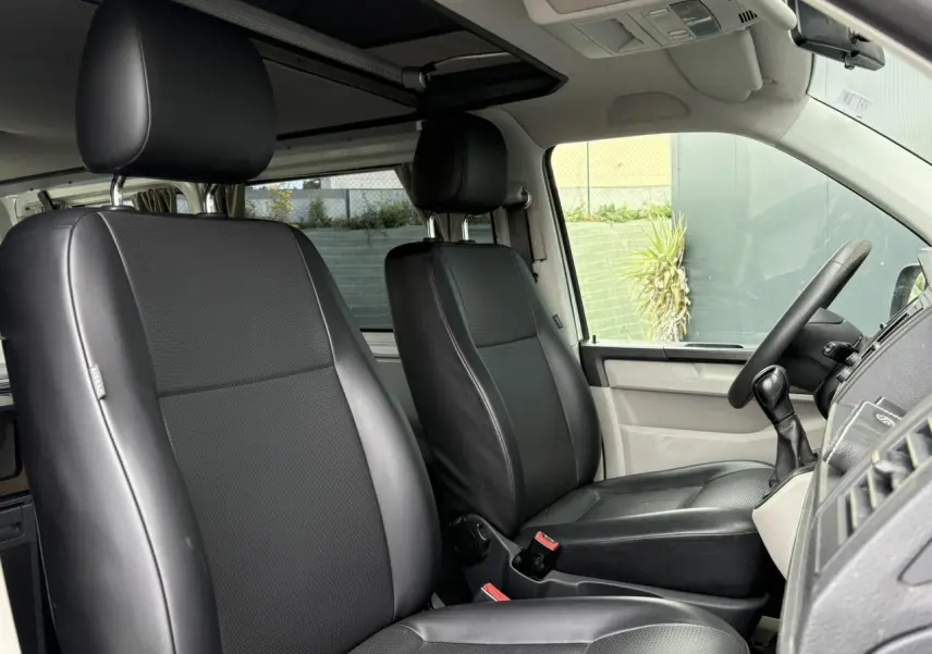 Intérieur du Volkswagen Transporter 2017, vue côté conducteur, sièges confort pivotants en cuir noir.