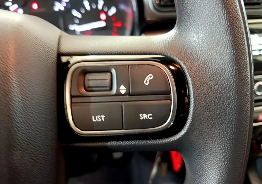 Gros plan sur les commandes multifonctions du volant noir d'une Citroën C3 blanche PureTech 68 BVM Feel 2018.