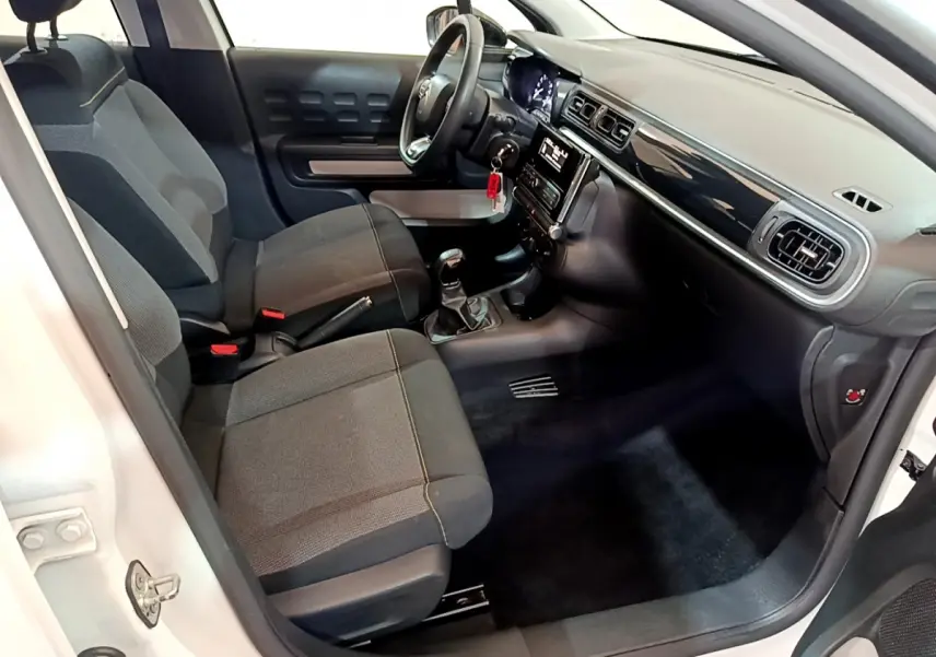 Intérieur avant de la Citroën C3 blanche 2018, vue côté conducteur montrant sièges tissu et tableau de bord noir brillant.