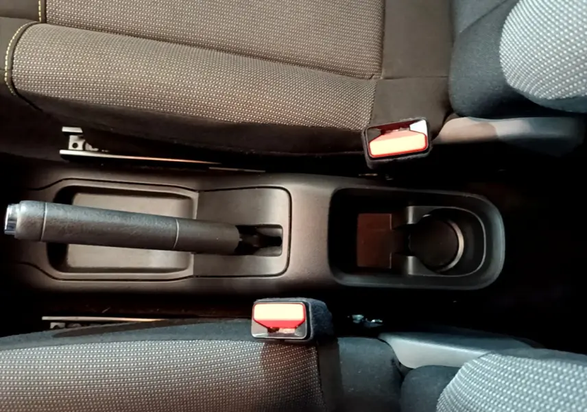 Vue plongeante sur la console centrale noire de la Citroën C3 2018, montrant frein à main et ceintures rouges.