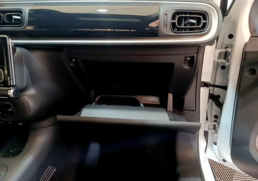 Intérieur de la Citroën C3 blanc 2018, vue côté passager avec boîte à gants ouverte et tableau de bord noir brillant.