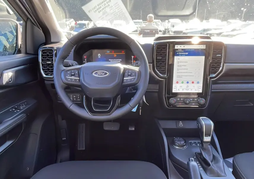 Vue intérieure du tableau de bord du Ford Ranger 2025 gris iconic, avec volant multifonction et écran tactile central vertical.