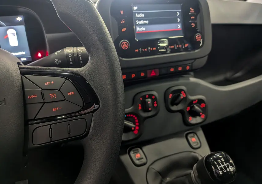 Vue rapprochée de l'intérieur de la Fiat Panda 1.0 Hybrid 2025, volant et console centrale avec boîte manuelle.