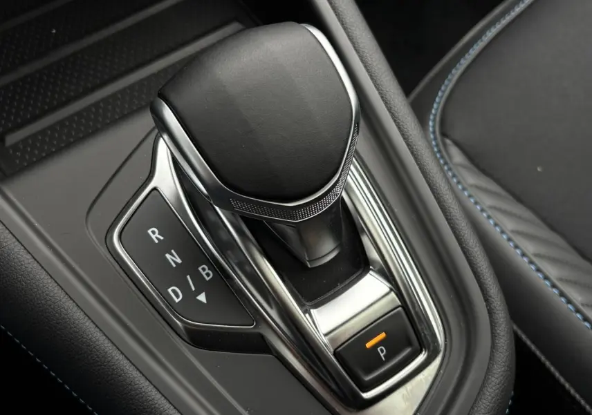 Le levier de vitesses automatique noir et chrome du Renault Captur E-Tech avec surpiqûres bleues sur la console.